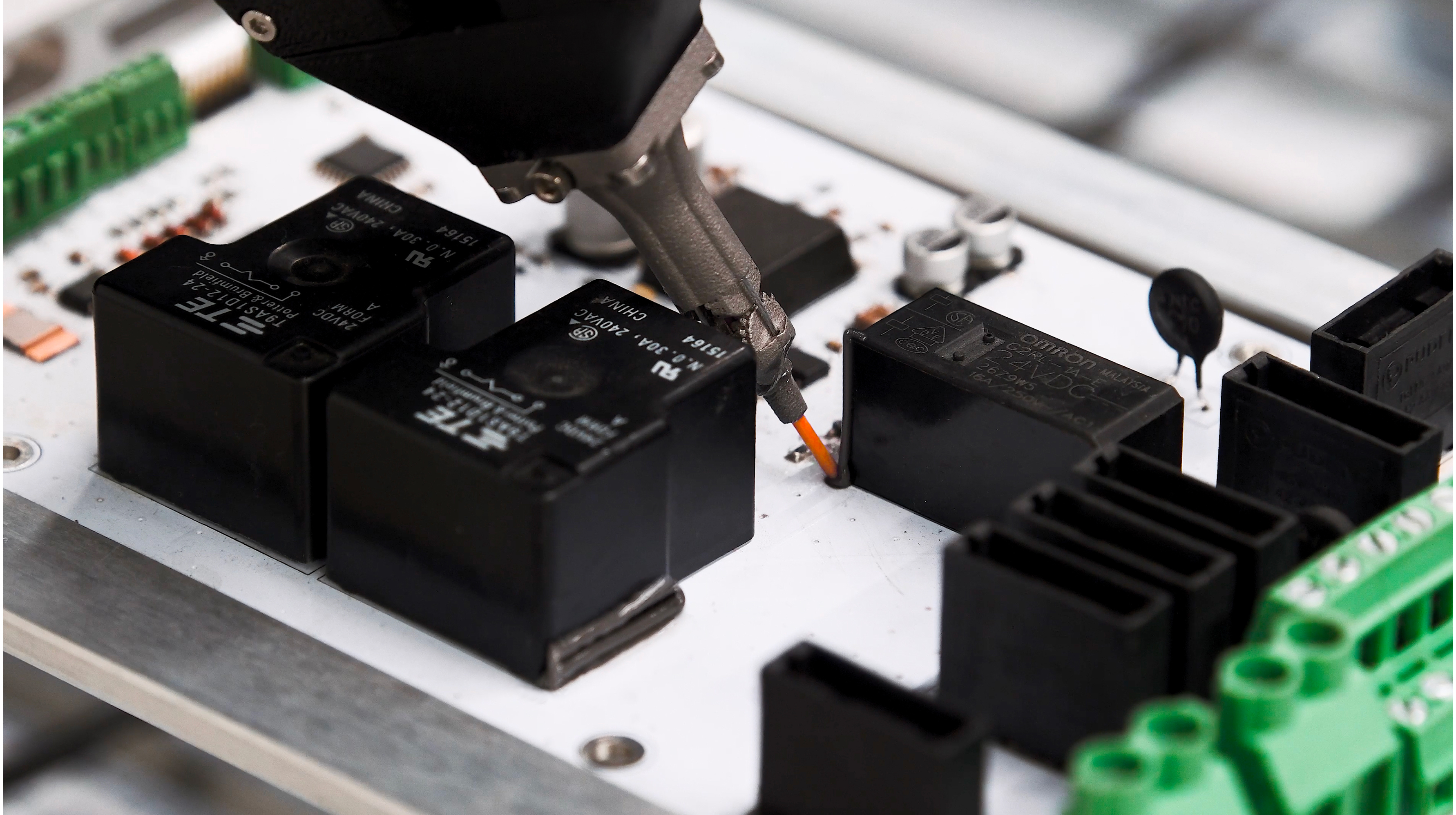 Adhesive dispensed between components on an electronic board